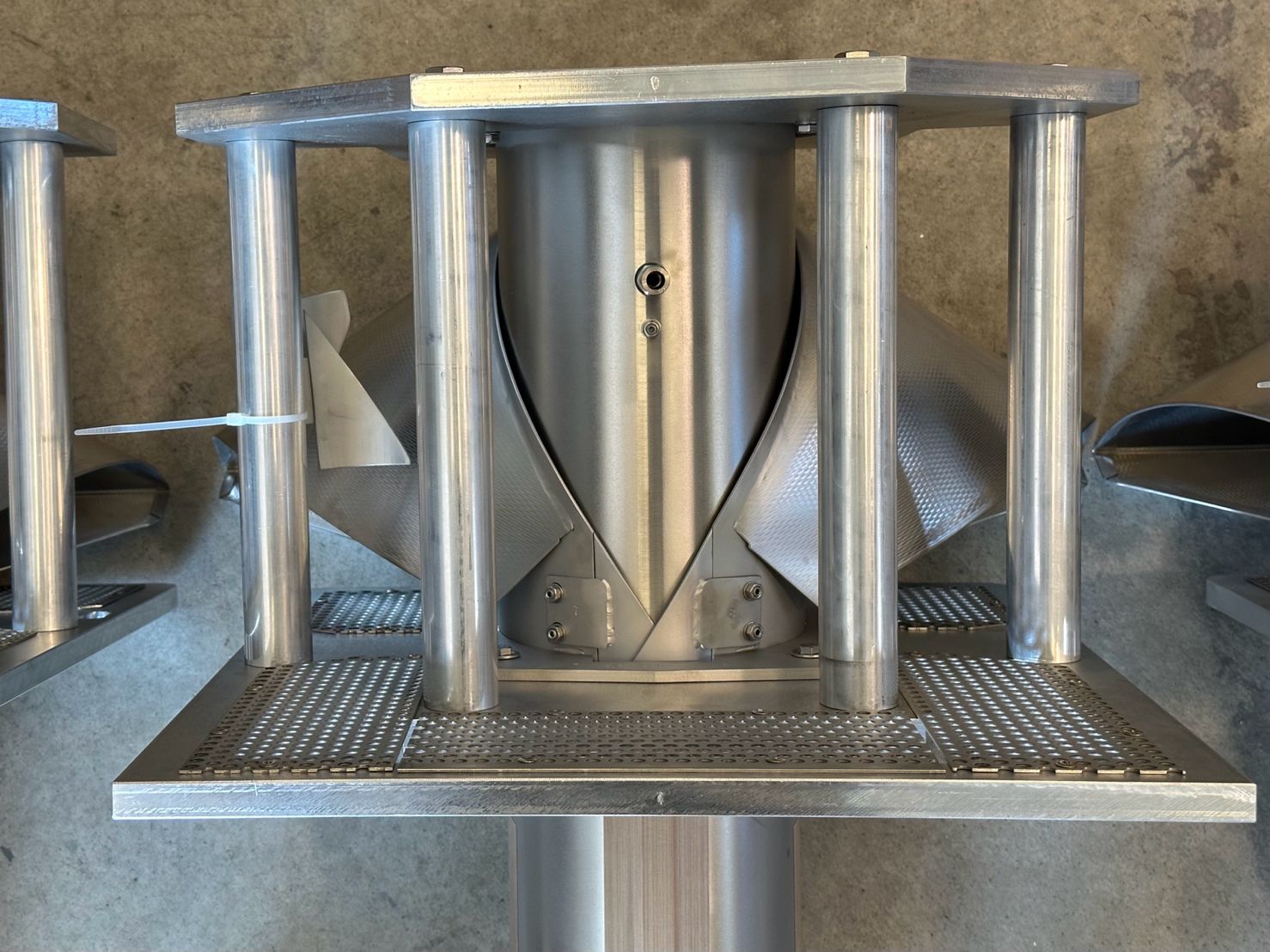 Tramoggia CN in acciaio inox con quattro colonne, piastre forate e convogliatori laterali goffrati su pavimento in cemento